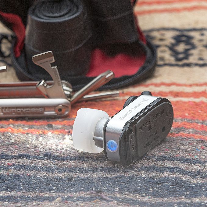 Lifestylefoto van de Blackburn Outpost lamp naast een multitool en fietstas, als onderdeel van een bikepacking-uitrusting.