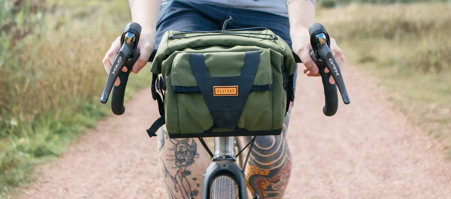 Point-of-view van een fietser met getatoeëerde benen die een Restrap Bar Pack bestuurt.
