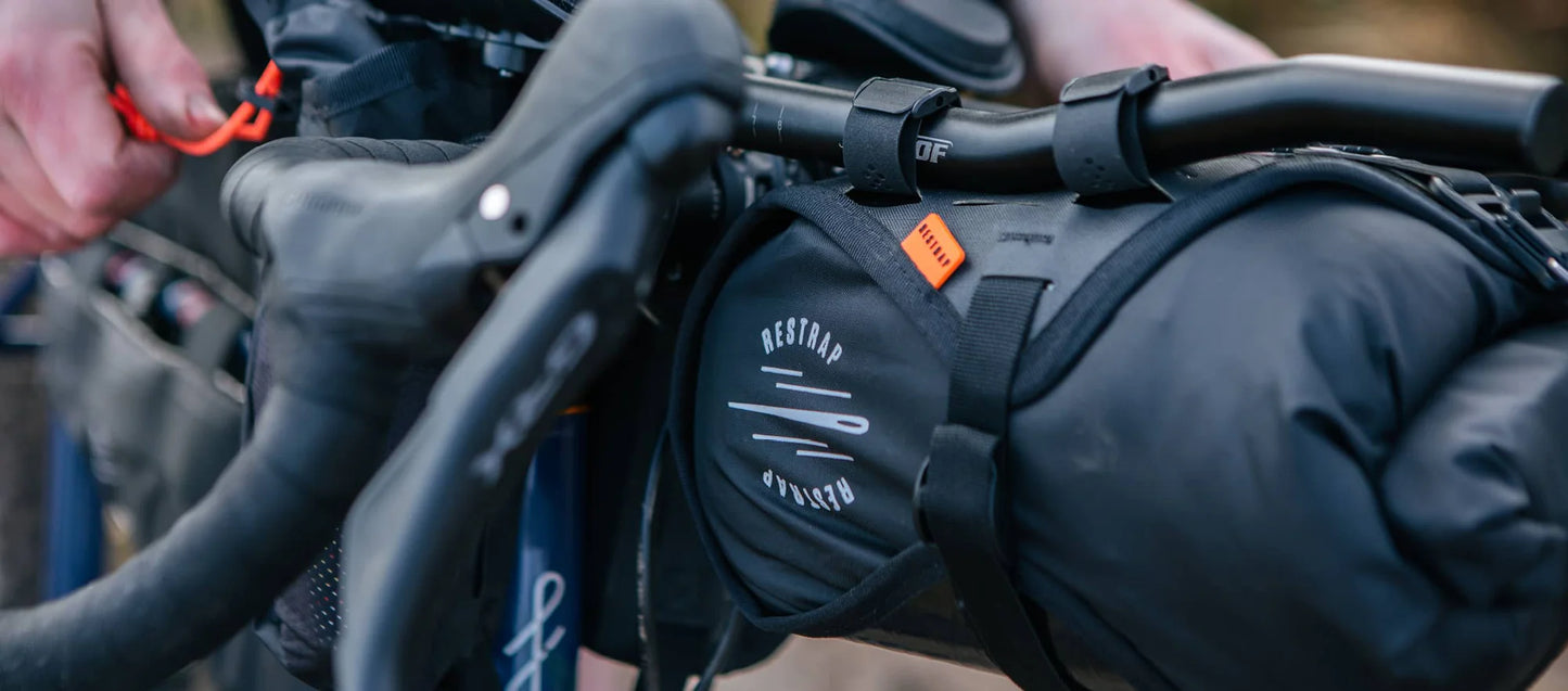 Een fietser opent de Restrap Race Aero Bar Bag tijdens een rit voor snelle toegang tot spullen.