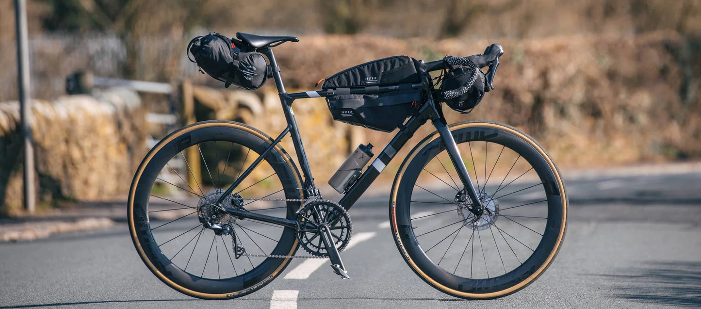 Volledig uitgeruste carbon racefiets met de Restrap Race Frame Bag small en andere bikepacking tassen in een landschap.