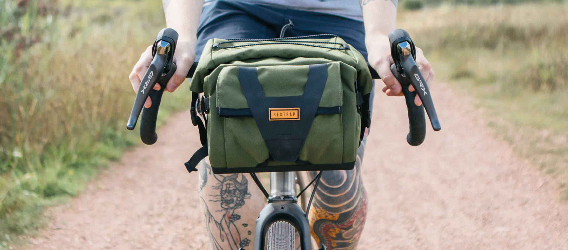 Point-of-view van een fietser met getatoeëerde benen die een Restrap Bar Pack bestuurt.