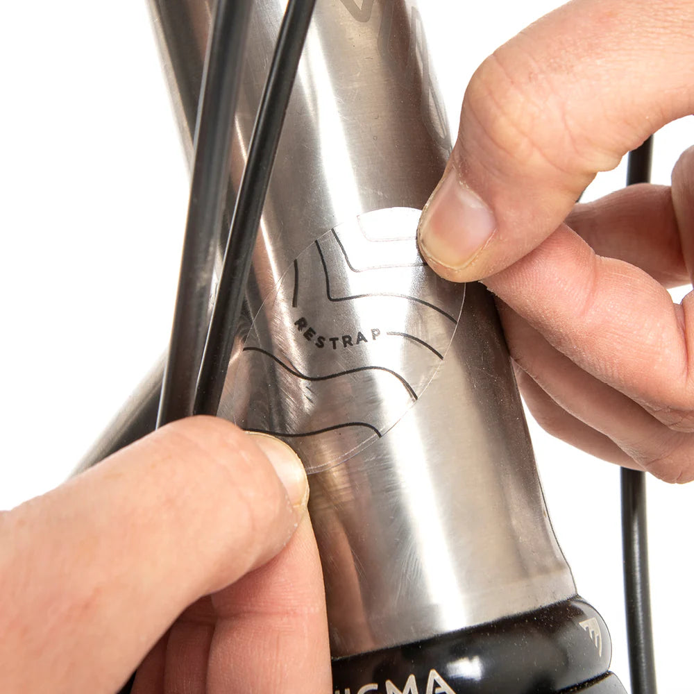 Close-up van het aanbrengen van een ronde Restrap sticker op het balhoofd om kabelslijtage te voorkomen.