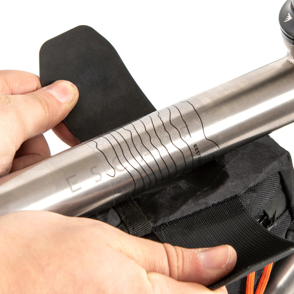 Een Restrap framebescherming sticker wordt aangebracht op de bovenbuis van een titanium fiets.